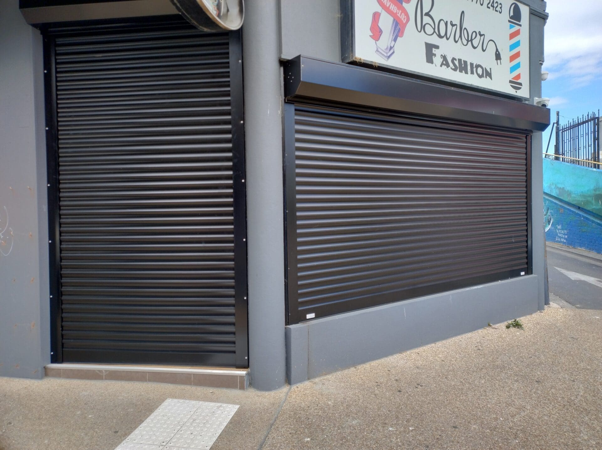 Electric Commercial Shutters a store front with a sign and a barber shop sign
